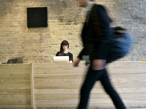 Receptionist at a desk while a person walks by.