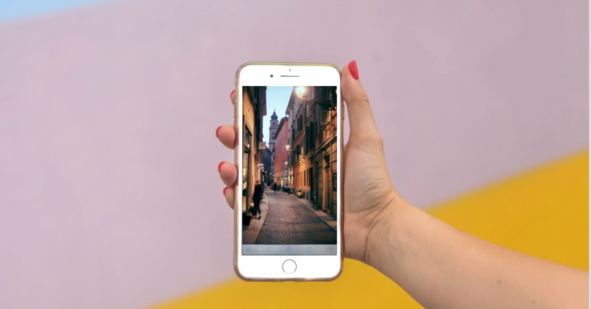 Hand holding a smartphone displaying a picturesque city street.